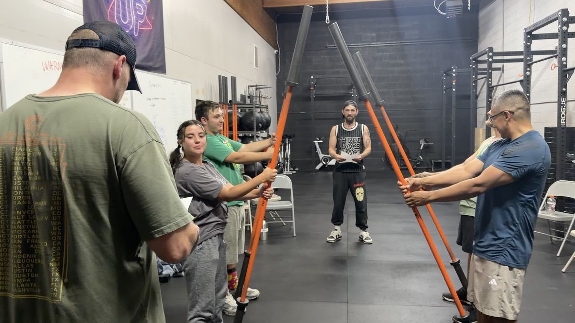 People holding training bars during the evening workout at Recovering Addict in Ogden